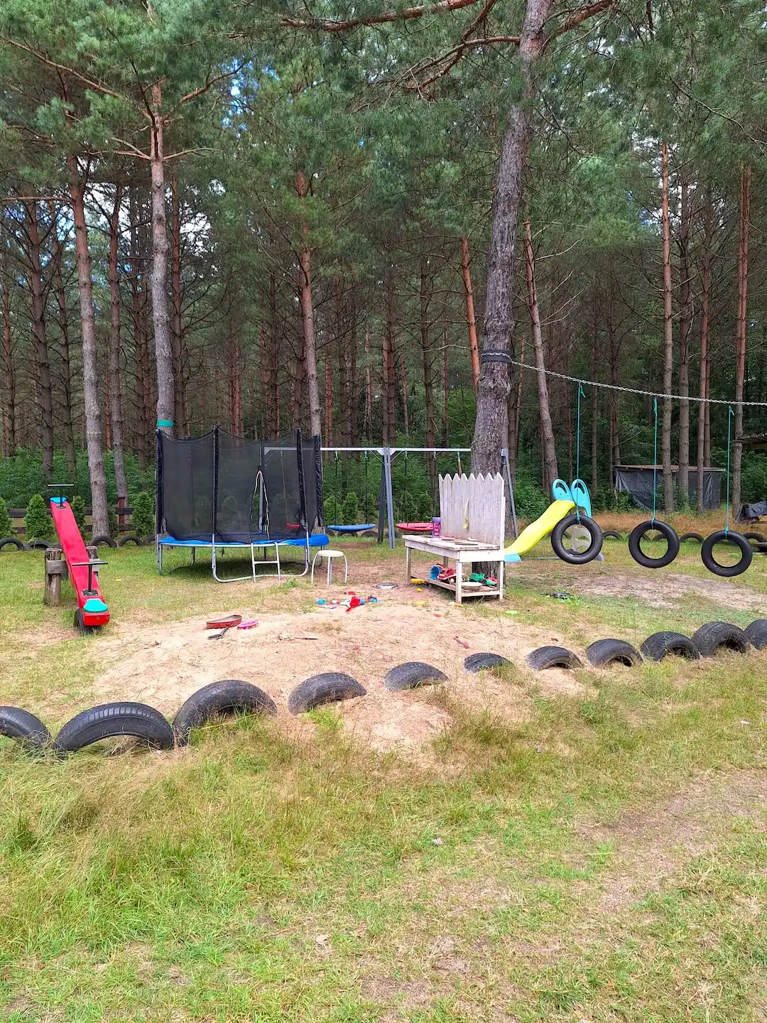 Plac zabaw z trampoliną, piaskownicą i drewnianą kuchnią dla dzieci
