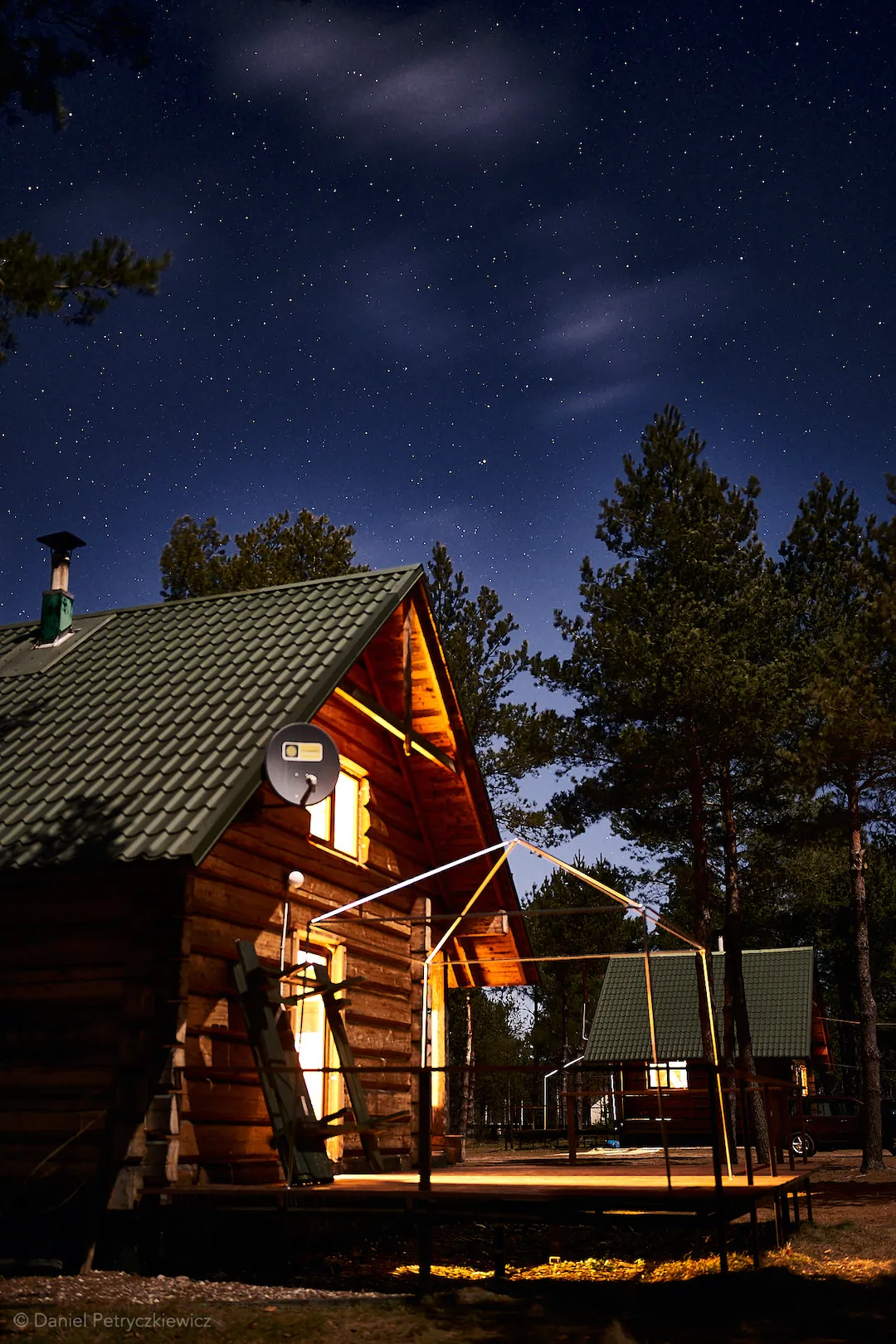 Oświetlony dom nocą na tle gwiaździstego nieba